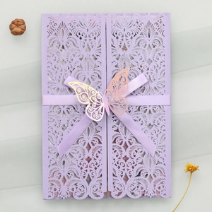 Détail macro du motif floral découpé au laser avec ruban violet et papillon sur invitation