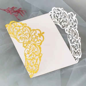Detail of laser-cut wedding invitation with golden glitter patterns and ivory cardstock