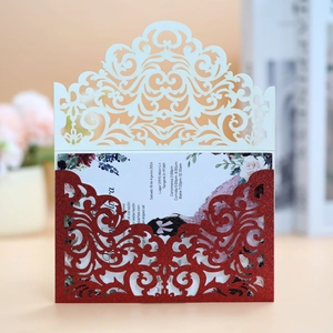 Detail of laser-cut wedding invitation with cream hollow cover and red glitter pocket