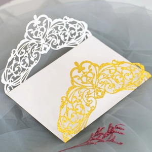 Macro shot of glitter gold laser cut wedding invitation with delicate lace details