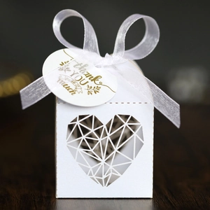 Détail de boîte à bonbons de mariage ivoire avec découpe de cœur et nœud en ruban