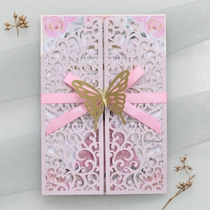 Détail de l'invitation de mariage découpée au laser avec ruban rose et papillon doré