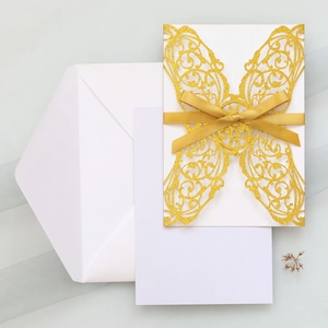 Detailed laser cut glitter gold invitation cover with elegant silk ribbon bow and envelope