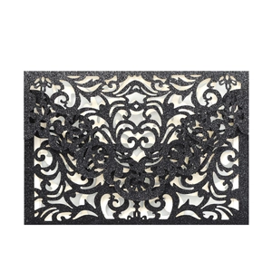 Close-up of laser-cut black glitter wedding invitation cover with intricate floral patterns