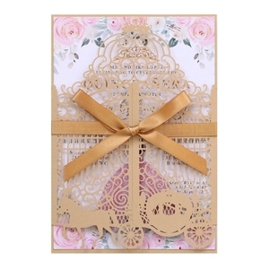 Detail of laser-cut pumpkin carriage wedding invitation with gold ribbon and floral insert