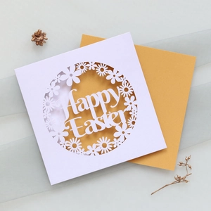 Close-up of laser-cut Happy Easter invitation card with daisy patterns on gold layer
