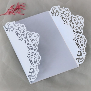 Macro detail of laser-cut floral lace patterns on a pearlescent wedding invitation cover