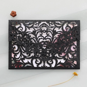 Detail showing baroque laser-cut wedding invitation with black glitter and floral patterns