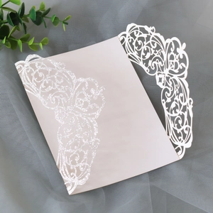 Close-up of laser-cut floral wedding invitation cover with elegant silver glitter details