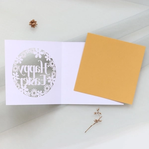 Laser-cut white Easter card featuring intricate floral patterns and golden inner paper