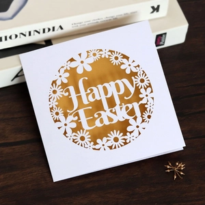 Macro shot of laser-cut Happy Easter card with golden liner and daisy pattern