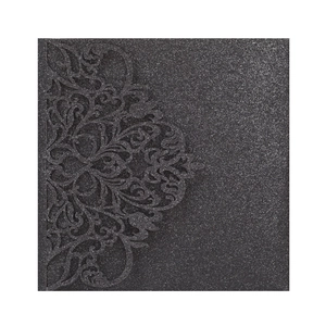 Detail of laser-cut black glitter wedding invitation with elegant floral hollow patterns