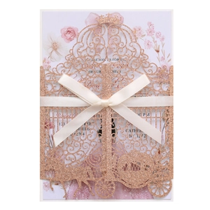 Detail of rose gold laser-cut wedding invitation with glitter finish and satin bow
