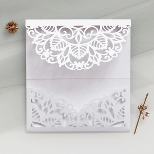 Laser-cut white wedding invitation with intricate floral hollow lace patterns and textures