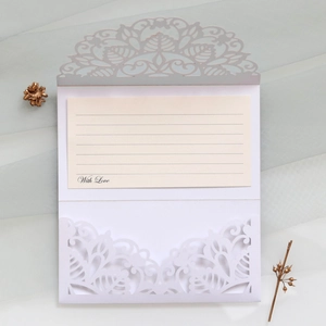 Detail view of laser-cut floral wedding invitation with mandala pattern and envelope