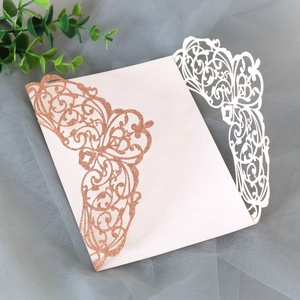Close-up of laser-cut rose gold glitter and white wedding invitation cover detail