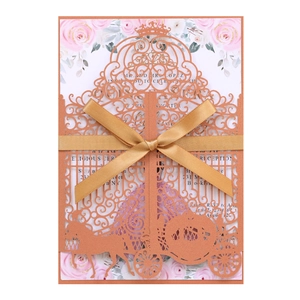 Detail of rose gold laser-cut invitation with crown, carriage motifs and gold ribbon bow