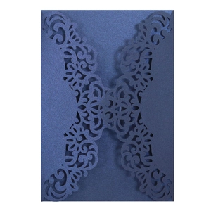 Close-up of navy blue laser-cut invitation sleeve with intricate floral scrollwork