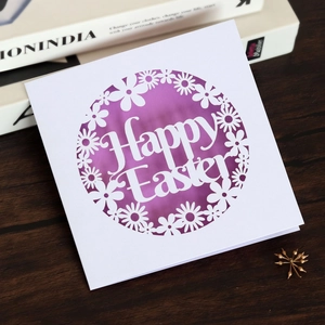 Detail of laser-cut Happy Easter card with white daisy pattern on a purple background