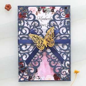 Détail d'invitation de mariage découpée au laser avec papillon doré et ruban de satin