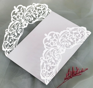 Detail of laser-cut grey invitation cover with white floral patterns and red dried flowers