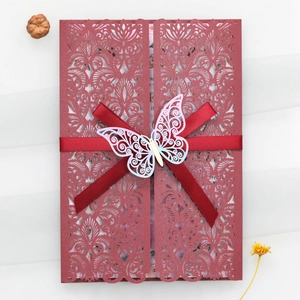 Détail de l'invitation de mariage découpée au laser avec ruban rouge et papillon argenté