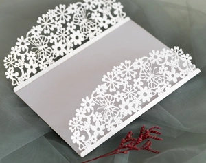 Close-up of elegant white laser-cut butterfly invitation card with intricate floral details