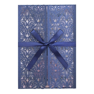 Détail d'invitation de mariage bleue découpée au laser avec un ruban élégant