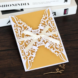 Intricate laser-cut butterfly wedding invitation with gold inner sheet and white ribbon