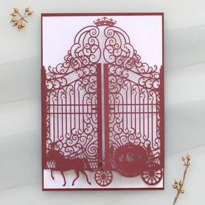 Macro detail of laser-cut crown and horse carriage patterns on red wedding invitations