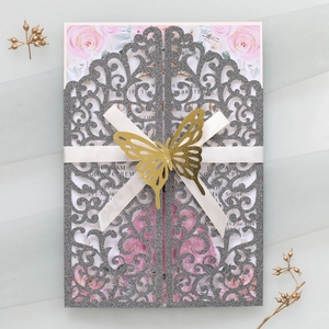 Vue macro de l'invitation de mariage découpée au laser avec papillon doré et ruban blanc