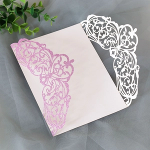 Detail of laser cut butterfly invitation cover with pink glitter and white floral patterns