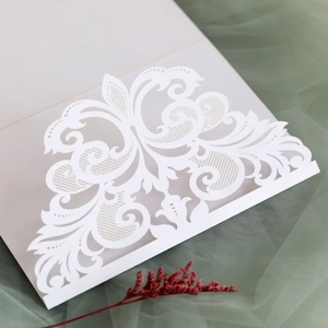 Close-up of elegant white laser-cut wedding invitation card with intricate lace details