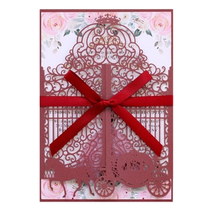 Detail of laser-cut burgundy wedding invitation with pink floral insert and red silk bow
