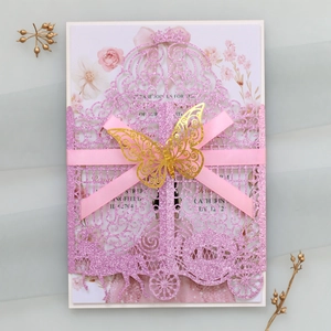 Detail of pink laser-cut wedding invitation with a golden glitter butterfly and ribbon