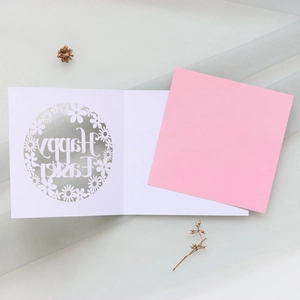 Detail of laser-cut Happy Easter floral card with pink insert on soft textured fabric