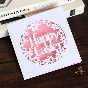 Detail of laser-cut floral daisy Easter card with pink inner layer on wooden background