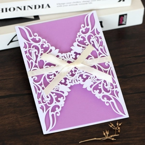 Detailed laser-cut invitation with purple insert and elegant white ribbon bow decoration