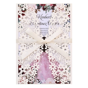 Detail of laser-cut hollow floral wedding invitation with ribbon and elegant inner page