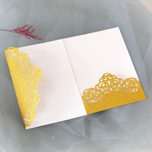 Macro shot of glittery gold laser-cut wedding invitation with elegant hollow patterns