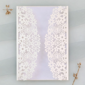 Detail showing laser-cut butterfly and flower pattern on elegant white wedding invitation