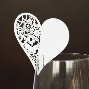 Macro detail of laser-cut white heart wine glass card with floral lace pattern