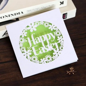 Detail of laser-cut Happy Easter card with green lining on a rustic wood table