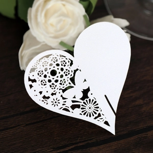 Macro detail of laser-cut floral pattern on white heart-shaped wedding place card