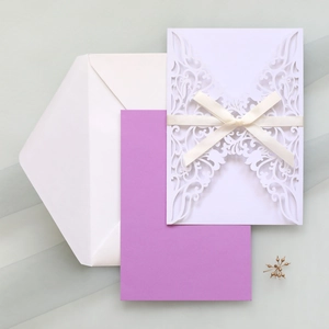 Laser-cut white wedding invitation with lavender insert, white ribbon, and matching envelope