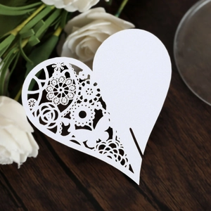 Detailed macro view of laser-cut heart place card with intricate white lace floral patterns