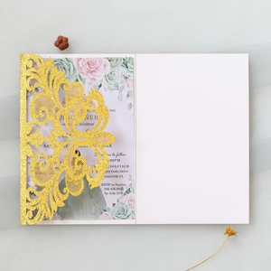 Macro detail of laser-cut gold glitter wedding invitation with floral vine pattern