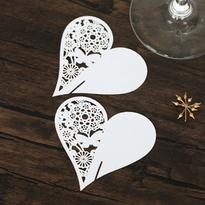 Detail of white laser-cut heart place cards with intricate butterfly and floral patterns
