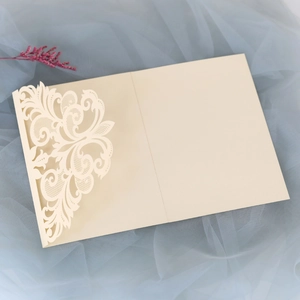 Macro detail of cream laser-cut wedding invitation with intricate floral lace pattern