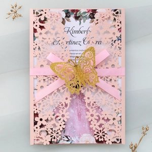Detail of pink laser-cut wedding invitation with golden 3D butterfly and ribbon
